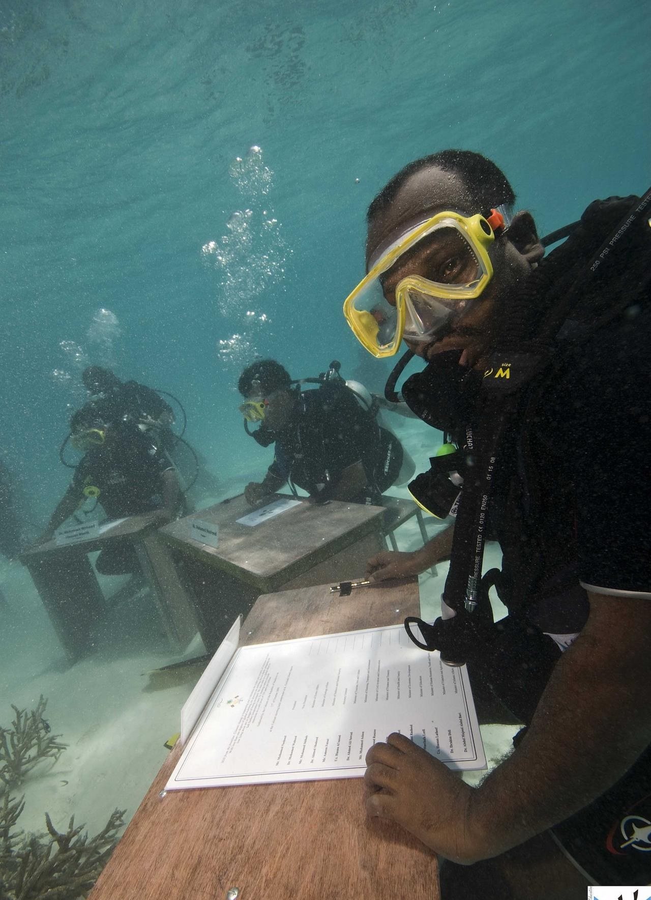 The 2009 Maldives underwater cabinet meeting, ministers in scuba gear at desks on the seafloor